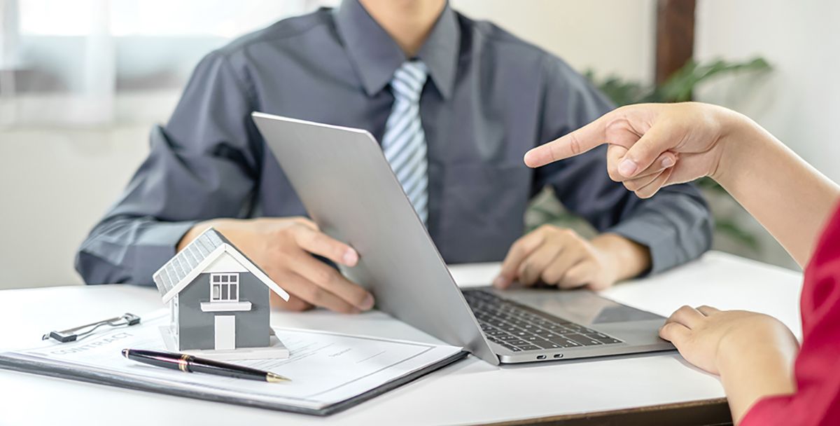 A real estate agent with a House model is talking to clients abo